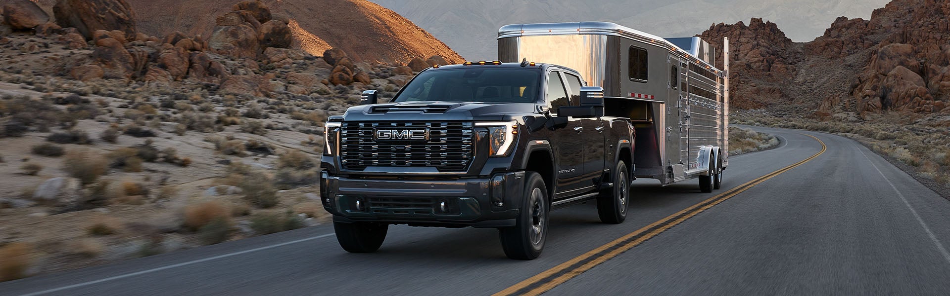 2024 GMC Sierra 2500HD with a trailer on a mountain road