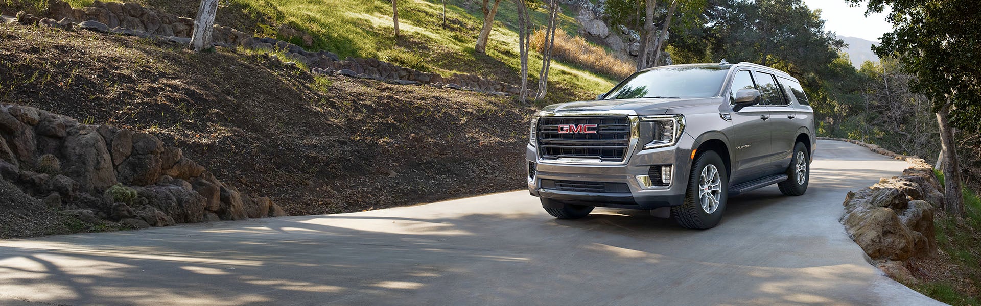 2024 GMC Yukon driving near a forest
